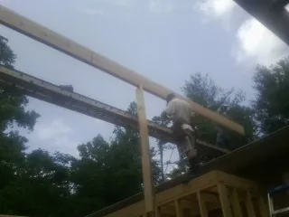 Carpenter setting a ridge beam over a new addition frame — Ice Dam Removal by Roofing Brothers in Saluda