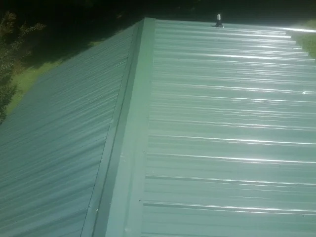 New green metal panels meeting at the ridge of a roof — Flat Roof Repair work by our crew in Saluda