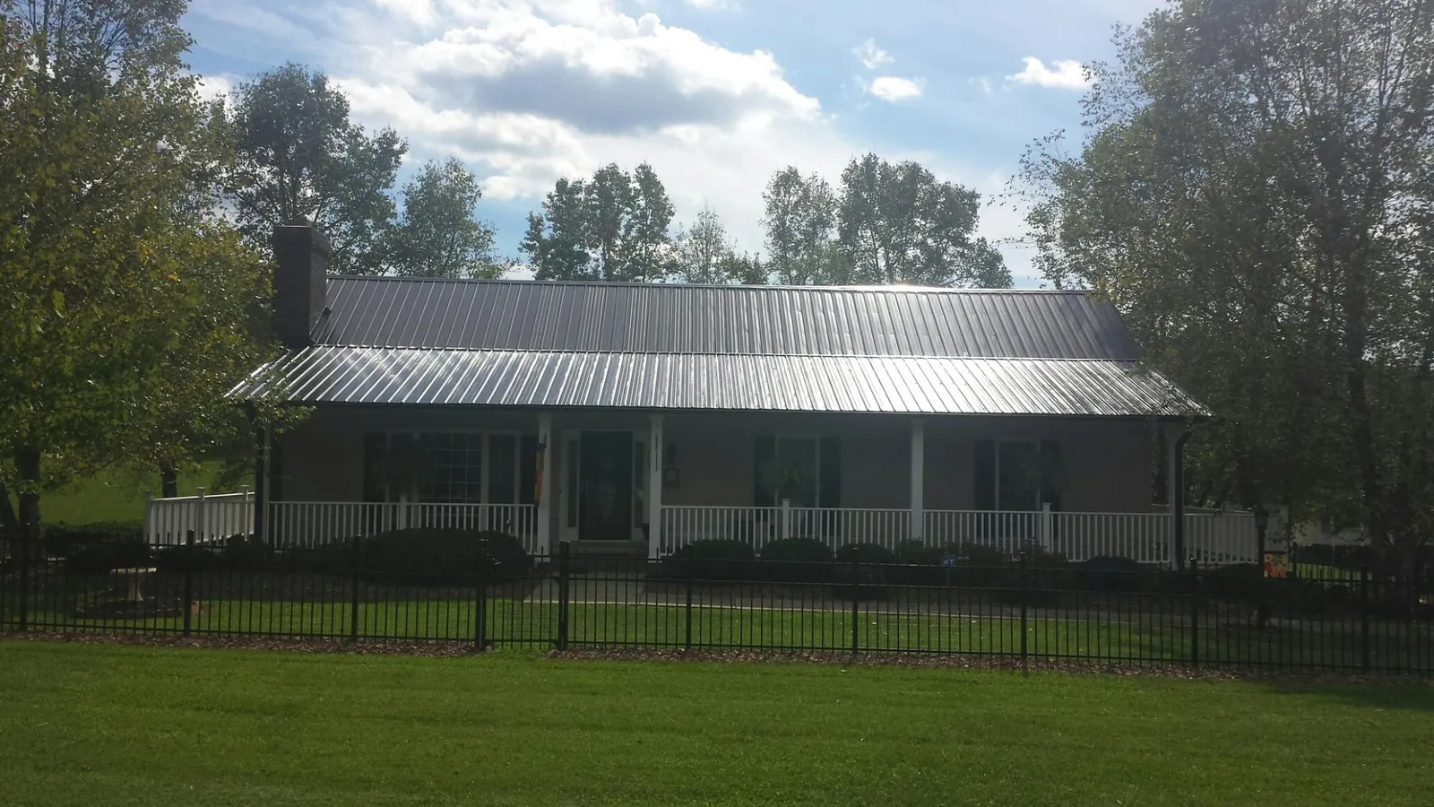Gray metal roof on a brick ranch with a full width front porch — Gutter Guard Installation work by our crew in Saluda